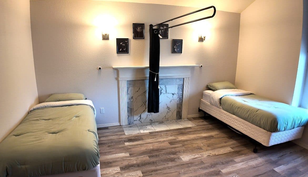Bedroom with two beds on either side of a fireplace and wall sconces