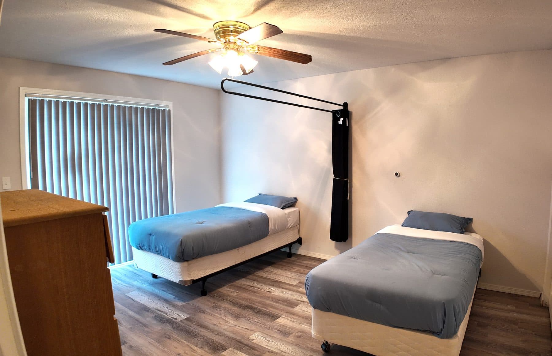 Semi-private bedroom with two beds, a dresser and a sliding door to the outside