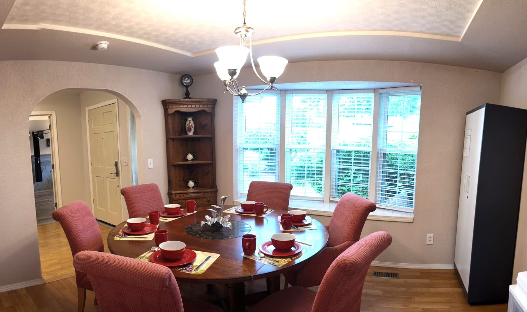 Dining area beneath a chandelier, with a bay window looking onto the garden